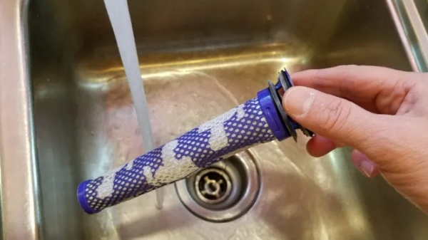 Dyson v6 filter being rinsed in a sink.